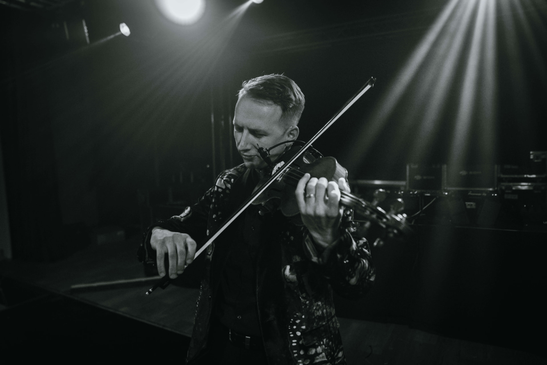 Černobílý detail Mr. Violingtona hrajícího na housle na jevišti